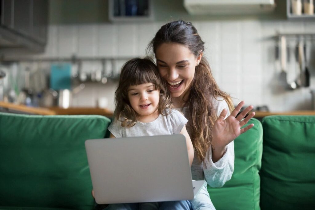 Picture of a nanny sitting with a child and looking at a computer screen.